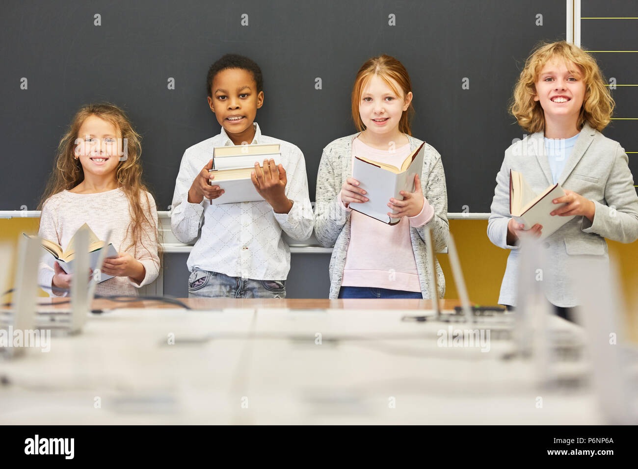 Group of children as pupils of a primary school study group with many books Stock Photo