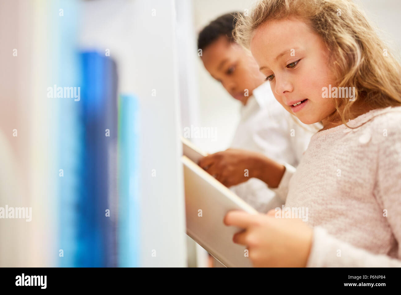 Children in elementary school reading and researching in books Stock Photo