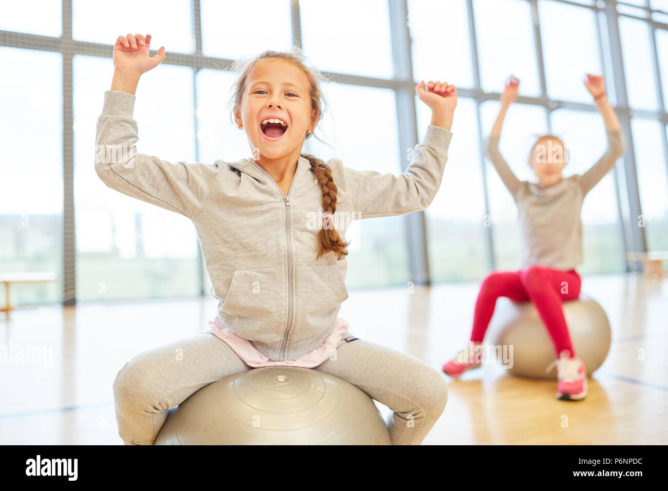 Two girls have fun in physical education with gym ball in the gym Stock Photo