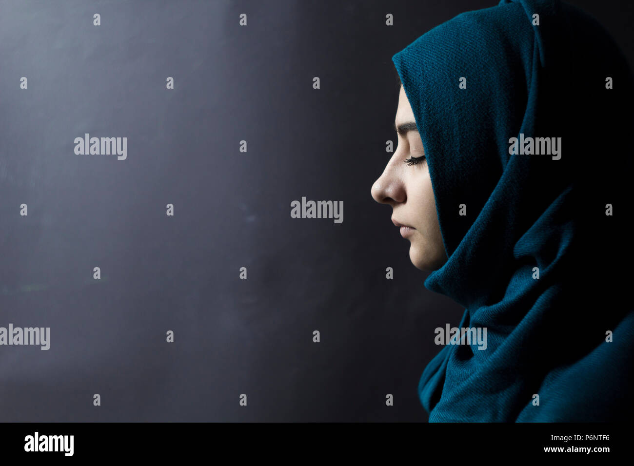 Arab girl in hijab on a black background. Sad Muslim female with closed eyes. Stock Photo
