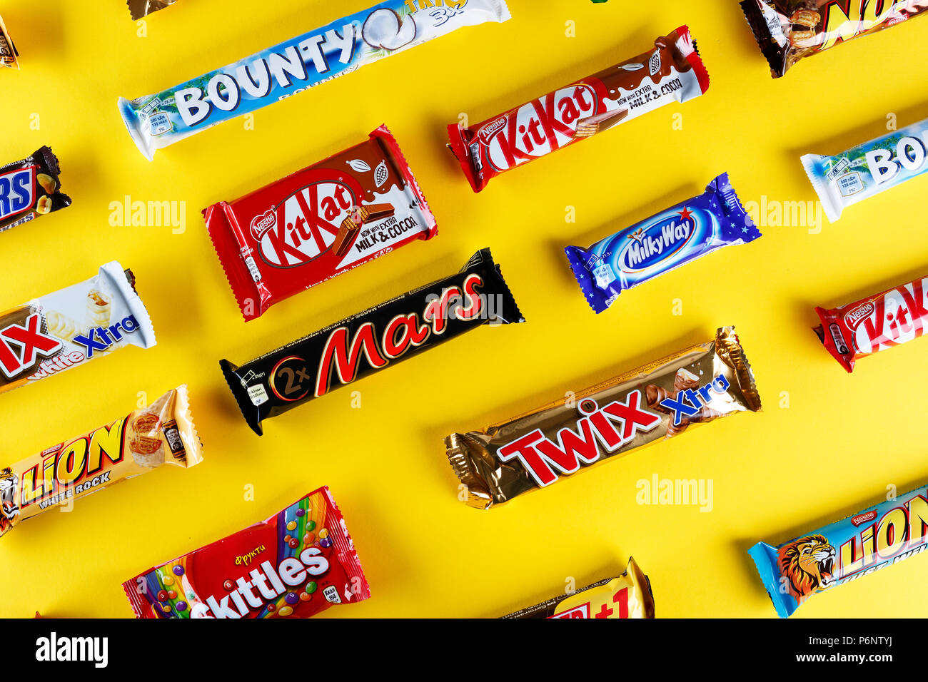 Kiev, Ukraine, March 29, 2018. different chocolate bars of modern companies. Chocolates lie in rows on a yellow background. Skittles - sweets, which a Stock Photo