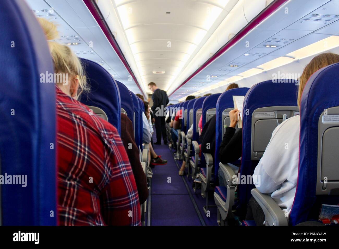 interior of a airplane with steward in aisle Stock Photo