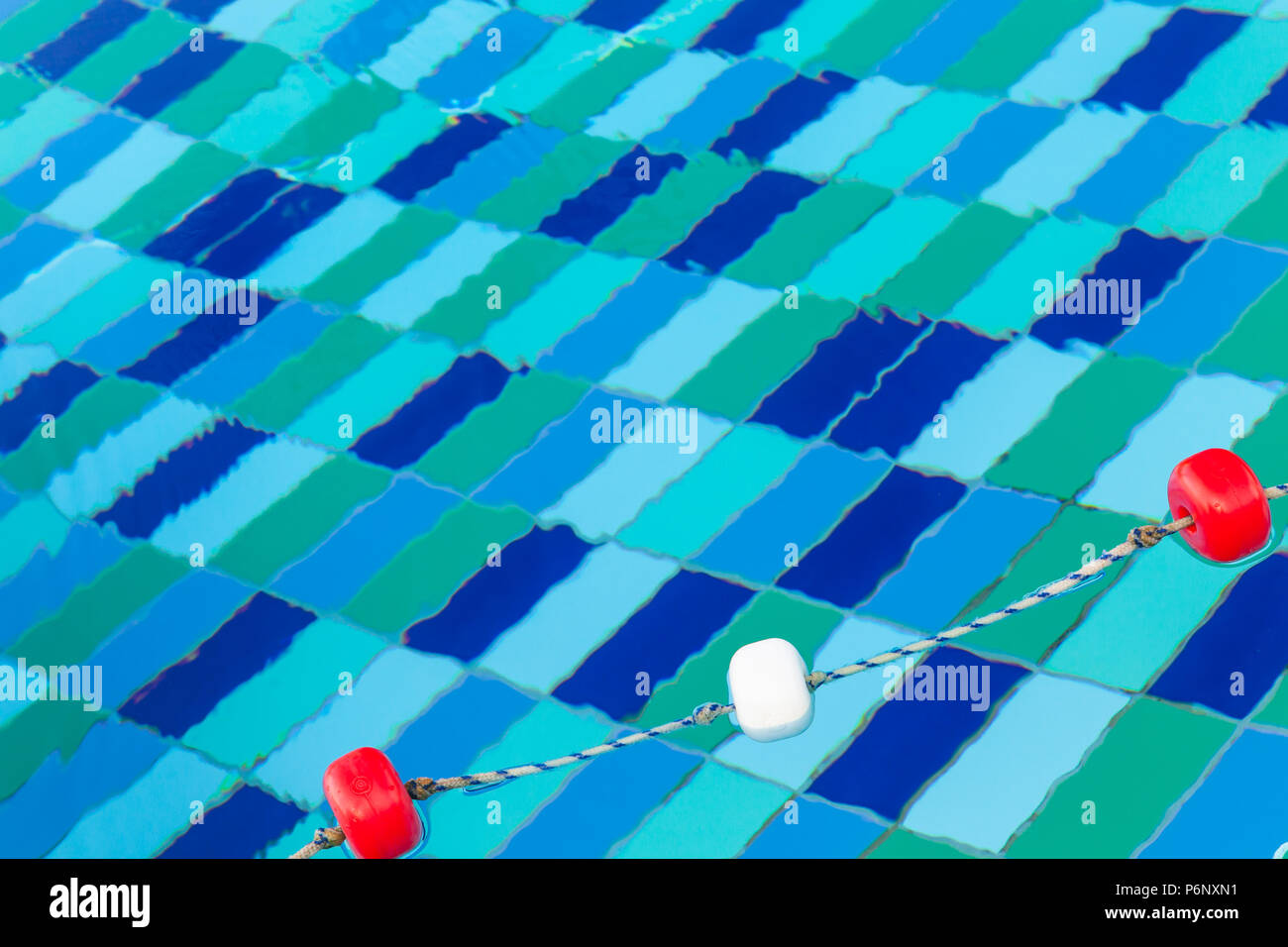 Red and white plastic floats on rope, swimming pool background Stock