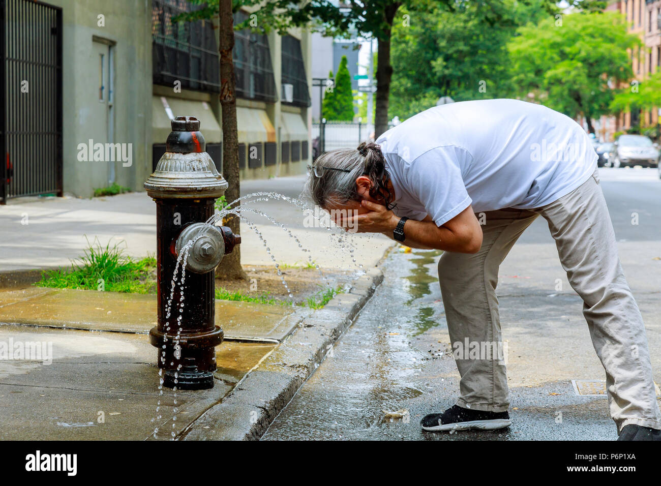 A man during a strong heat temperature is refreshed with Fire hydrant