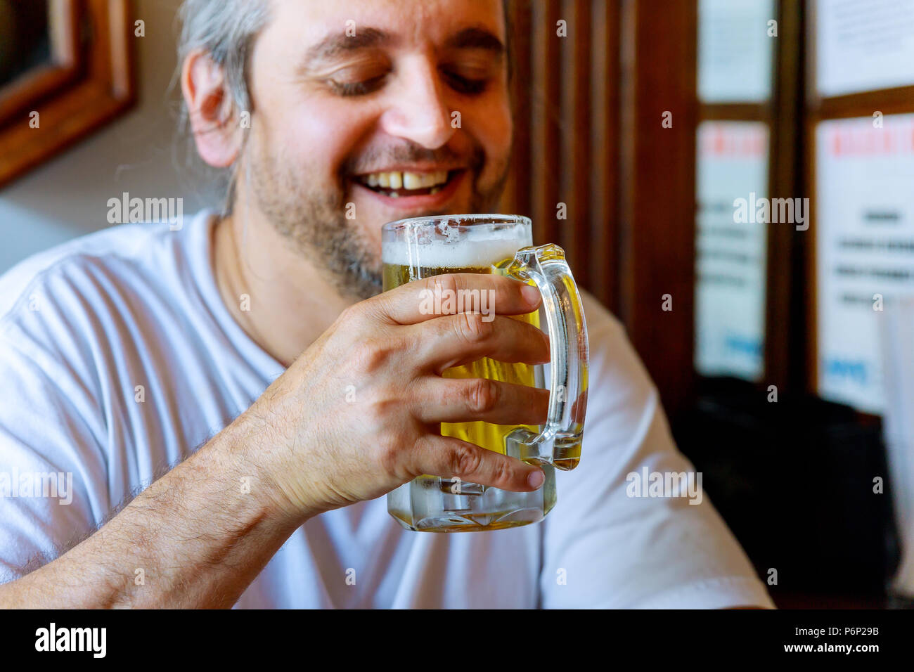 Drinking beer. Side view of handsome man drinking beer while sitting at