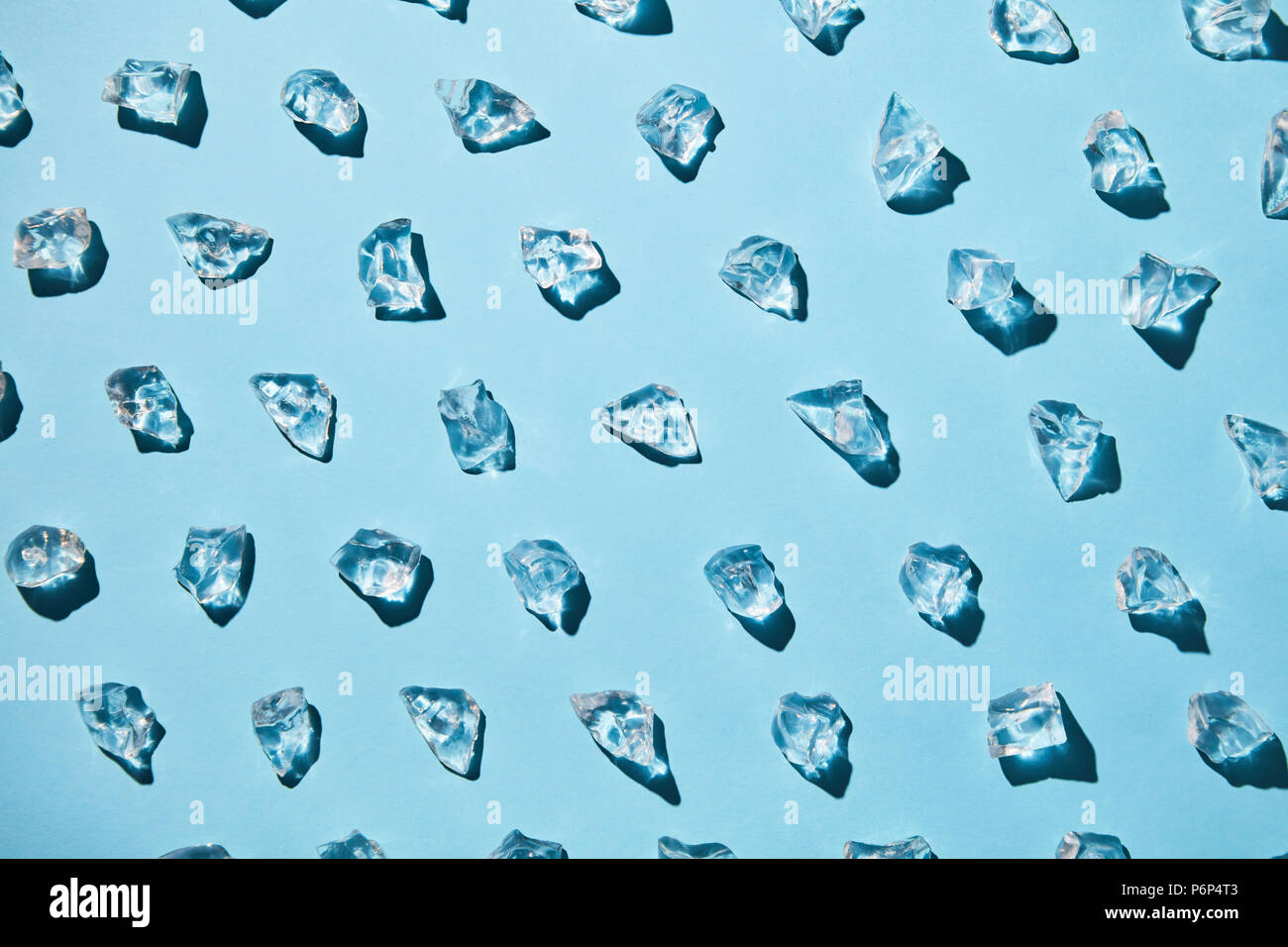 Transparent ice cubes with reflection of shadows on a blue paper ...