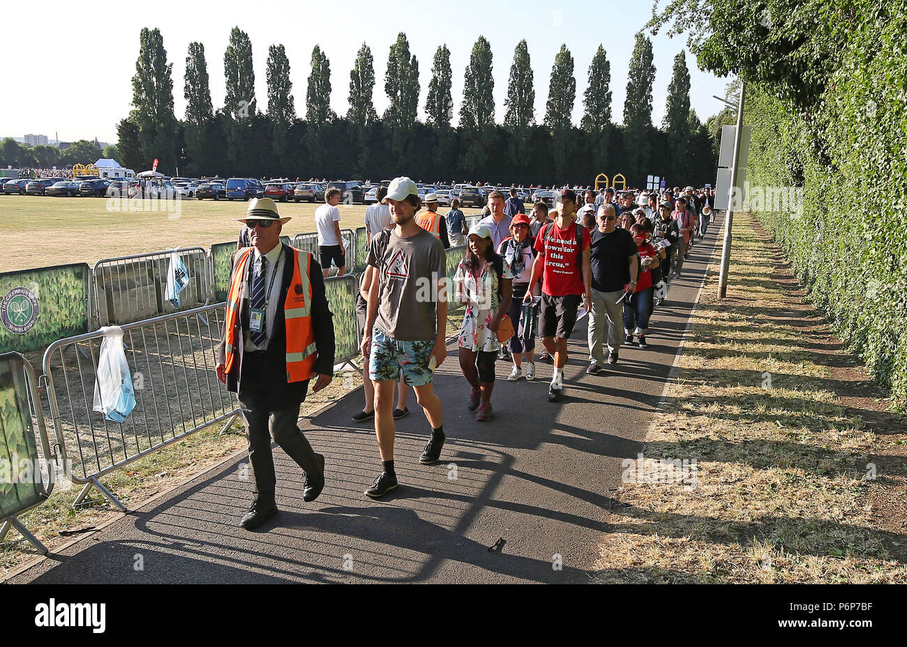 Darius Platt-Vowles, who is first in the queue, being led by a steward out of Wimbledon Park towards the main gate on day one of the Wimbledon Championships at the All England Lawn Tennis and Croquet Club, Wimbledon. Stock Photo