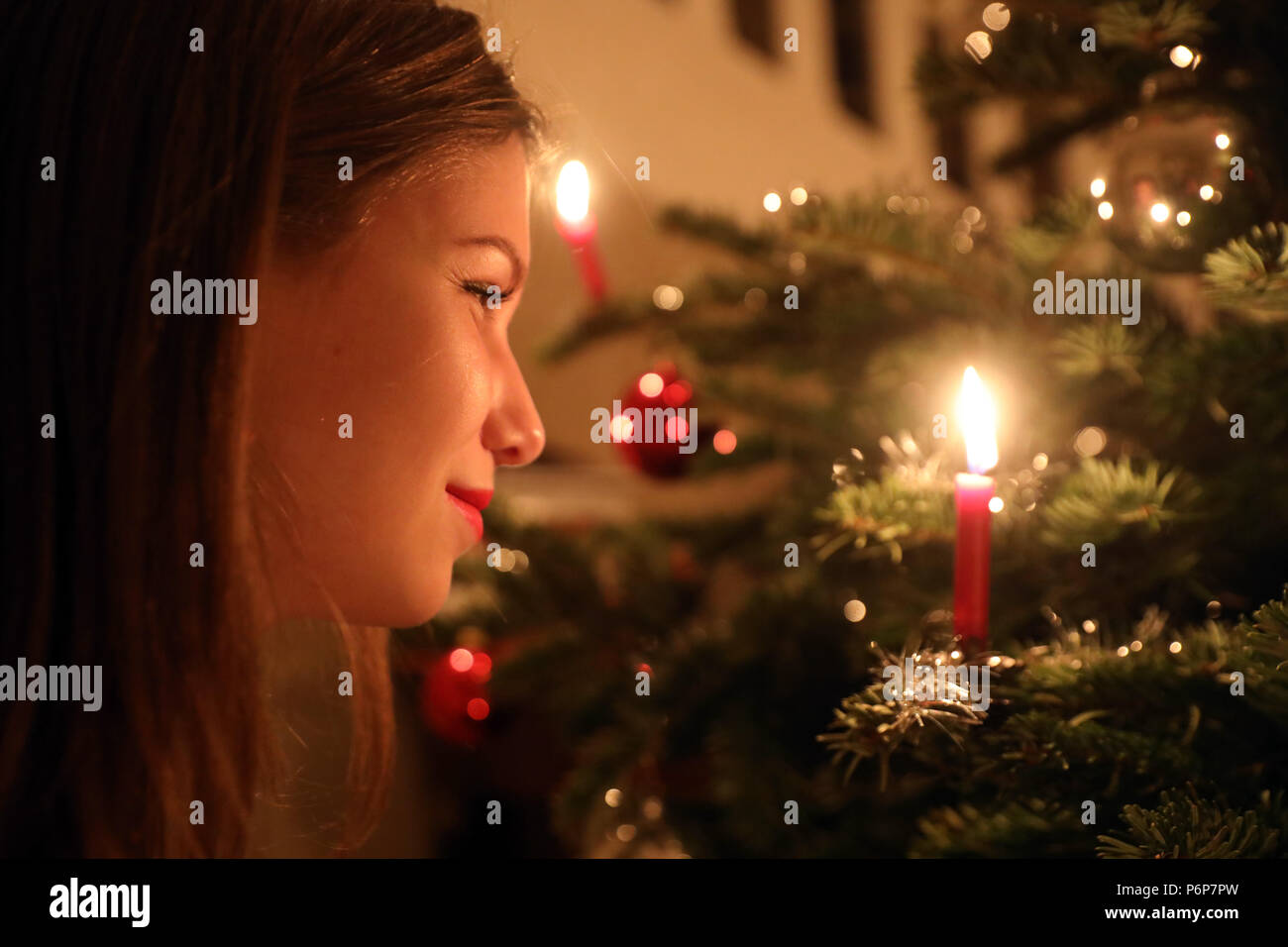 Girl looking at a candle on a Christmas tree.  Geneva. Switzerland. Stock Photo