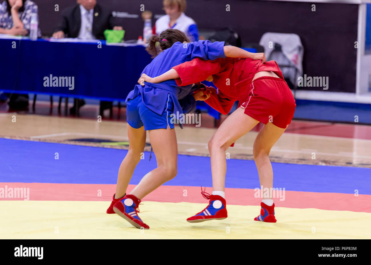 Two young girls compete in wrestling on tatami. Wrestling competition