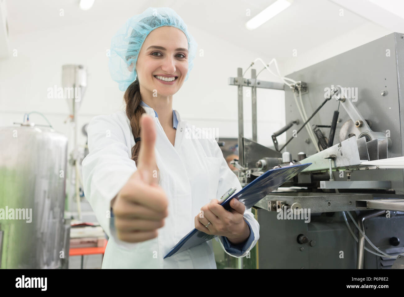 Portrait of happy woman manufacturing specialist showing thumbs up Stock Photo