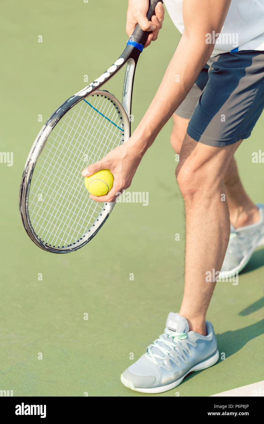 Low section of a professional player holding ball and tennis racket ...