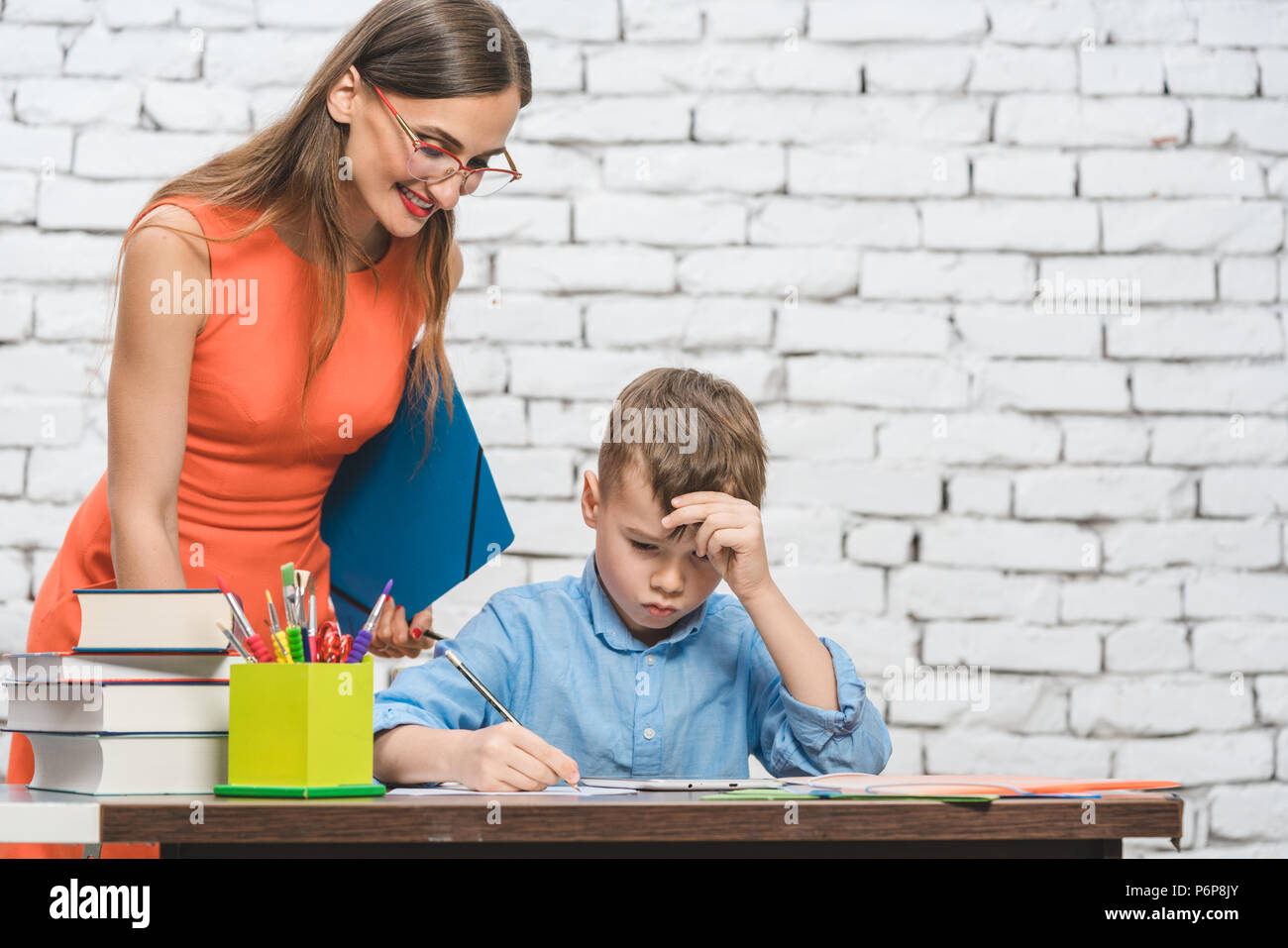 Student boy doing work in school supervised by his teacher Stock Photo