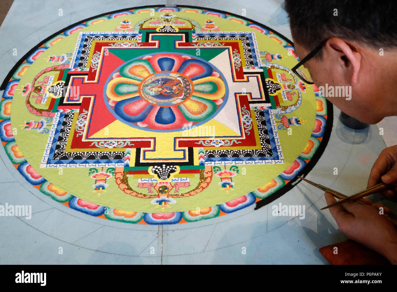 Tibetan monk working on sand mandala. Close-up. Stock Photo