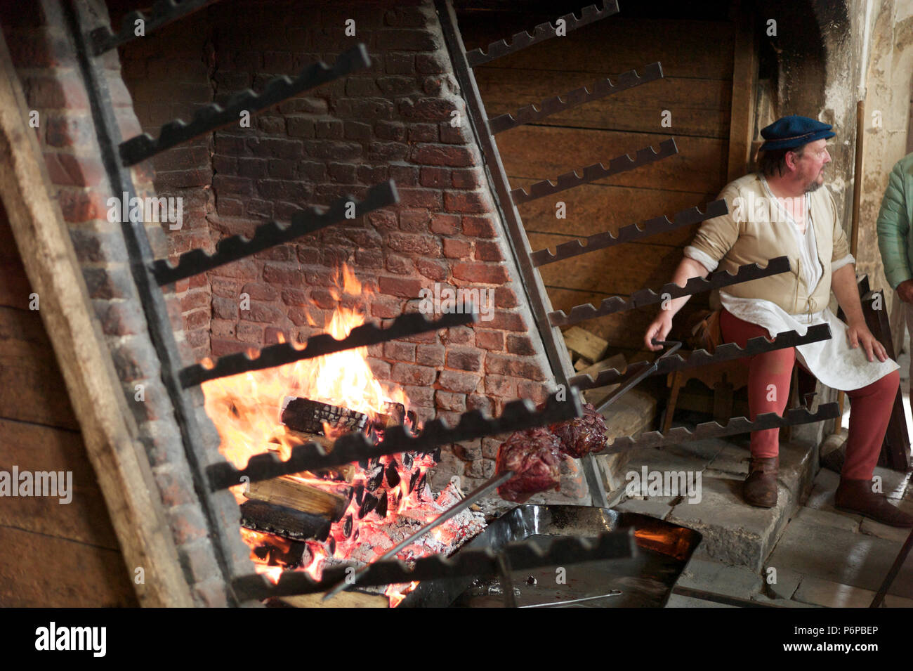 Renactment of open-fire cooking. Meat on a spit being cooked Stock Photo