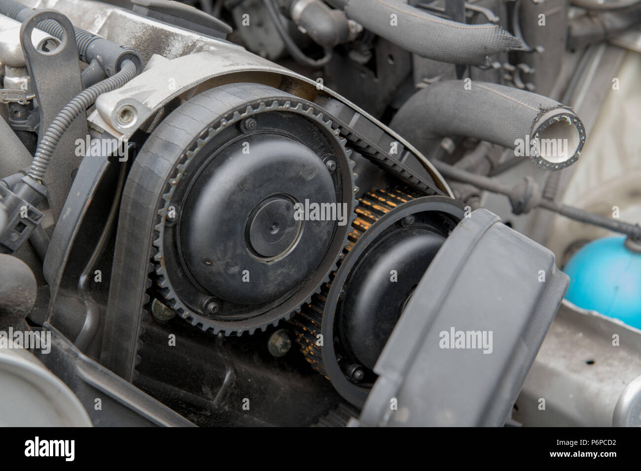 Automobile engine with side cover removed, exposing an old, cracked timing belt Stock Photo