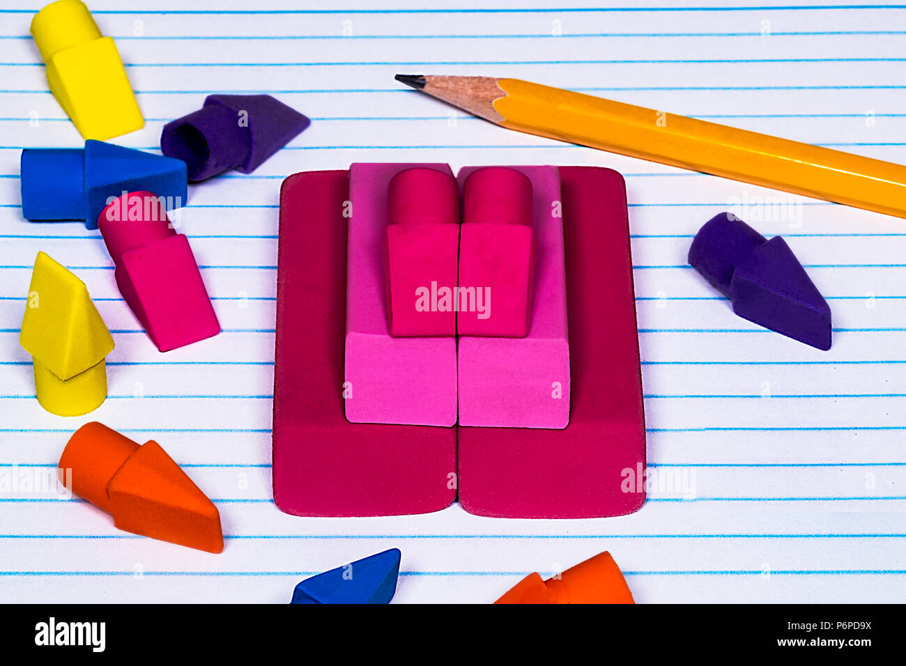 pencil erasers stacked and scattered on college ruled filler paper with