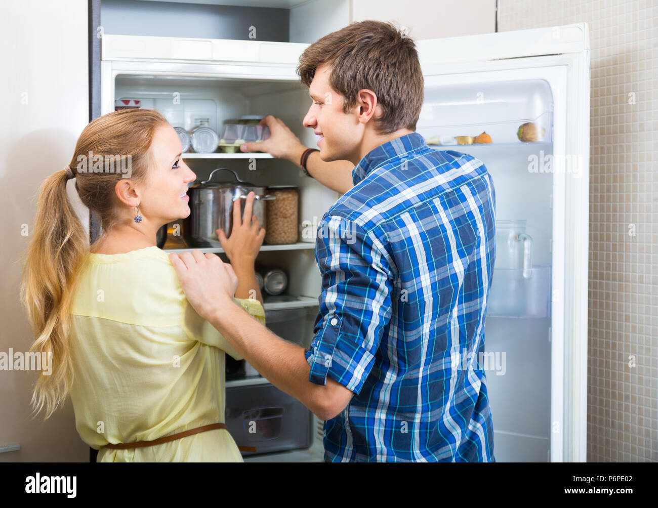 https://c8.alamy.com/comp/P6PE02/smiling-young-man-and-woman-standing-near-fridge-in-kitchen-P6PE02.jpg