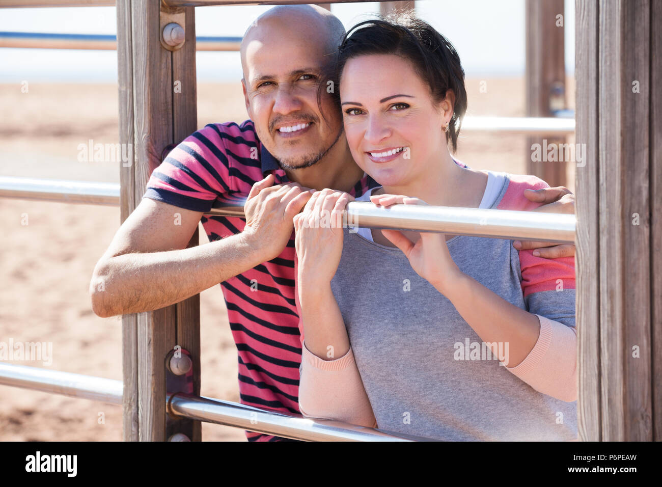 Happy man and woman standing together close to wall bars and smiling ...