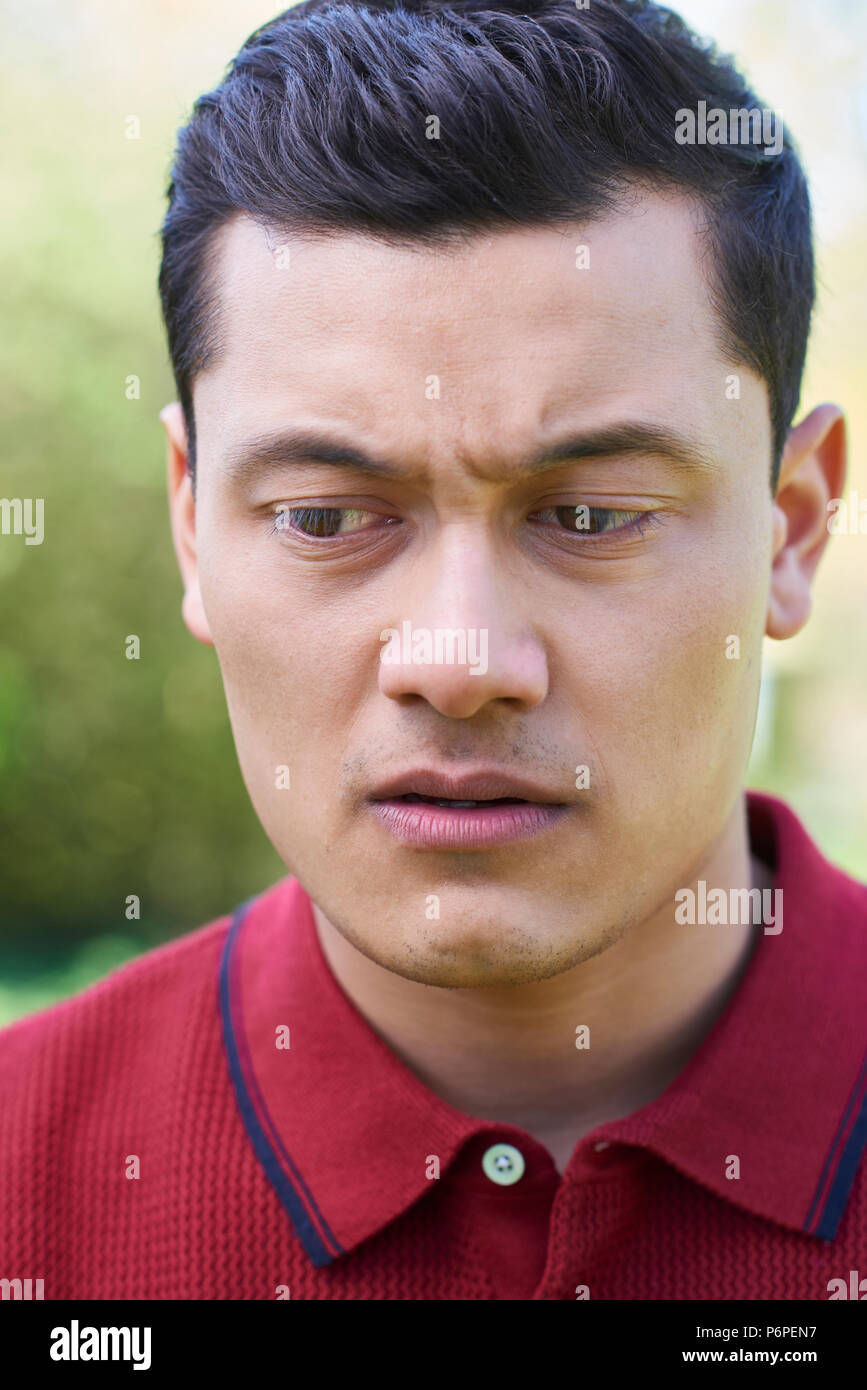 Outdoor Head And Shoulder Portrait Of Worried Young Man Stock Photo