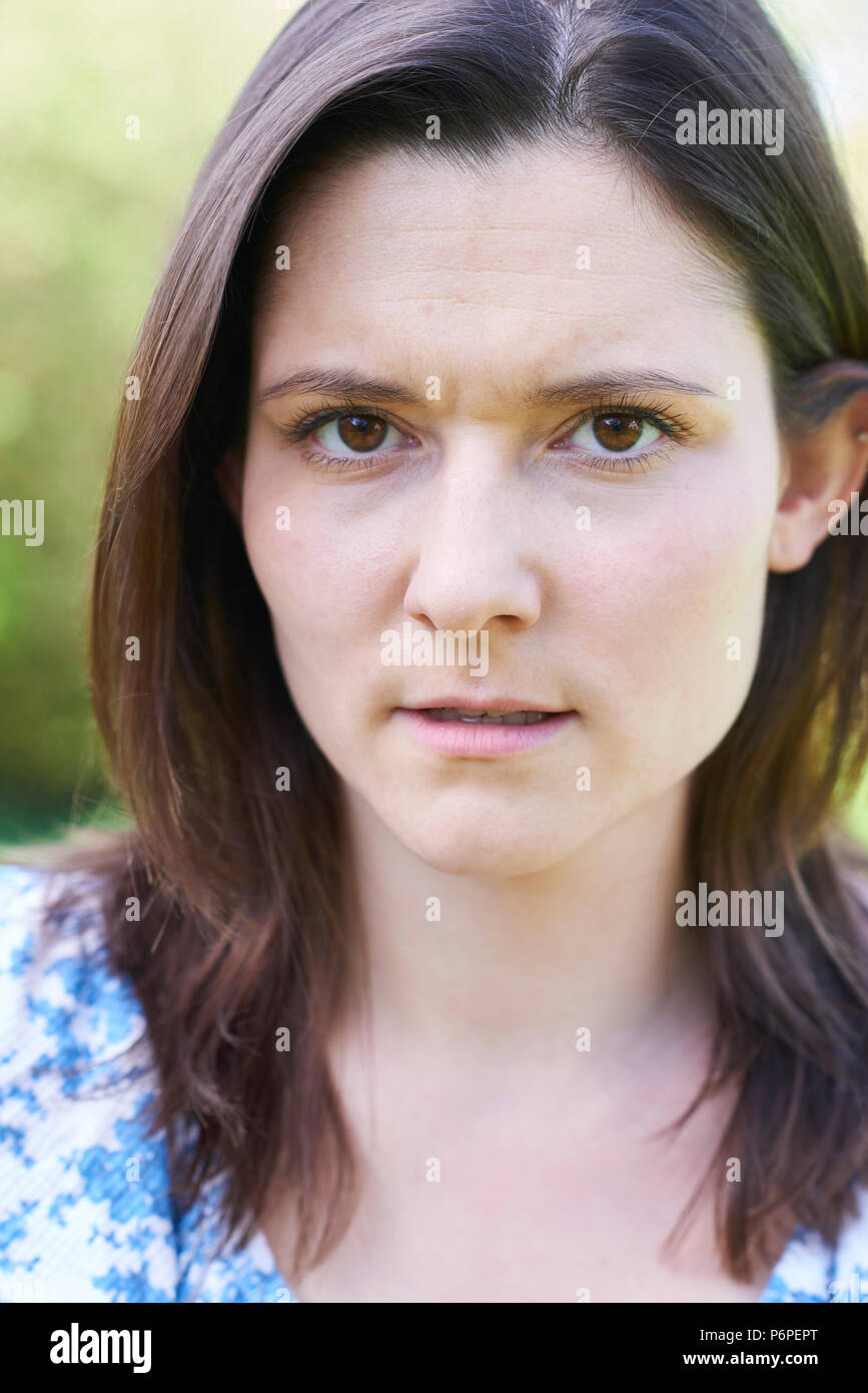 Outdoor Head And Shoulder Portrait Of Worried Young Woman Stock Photo