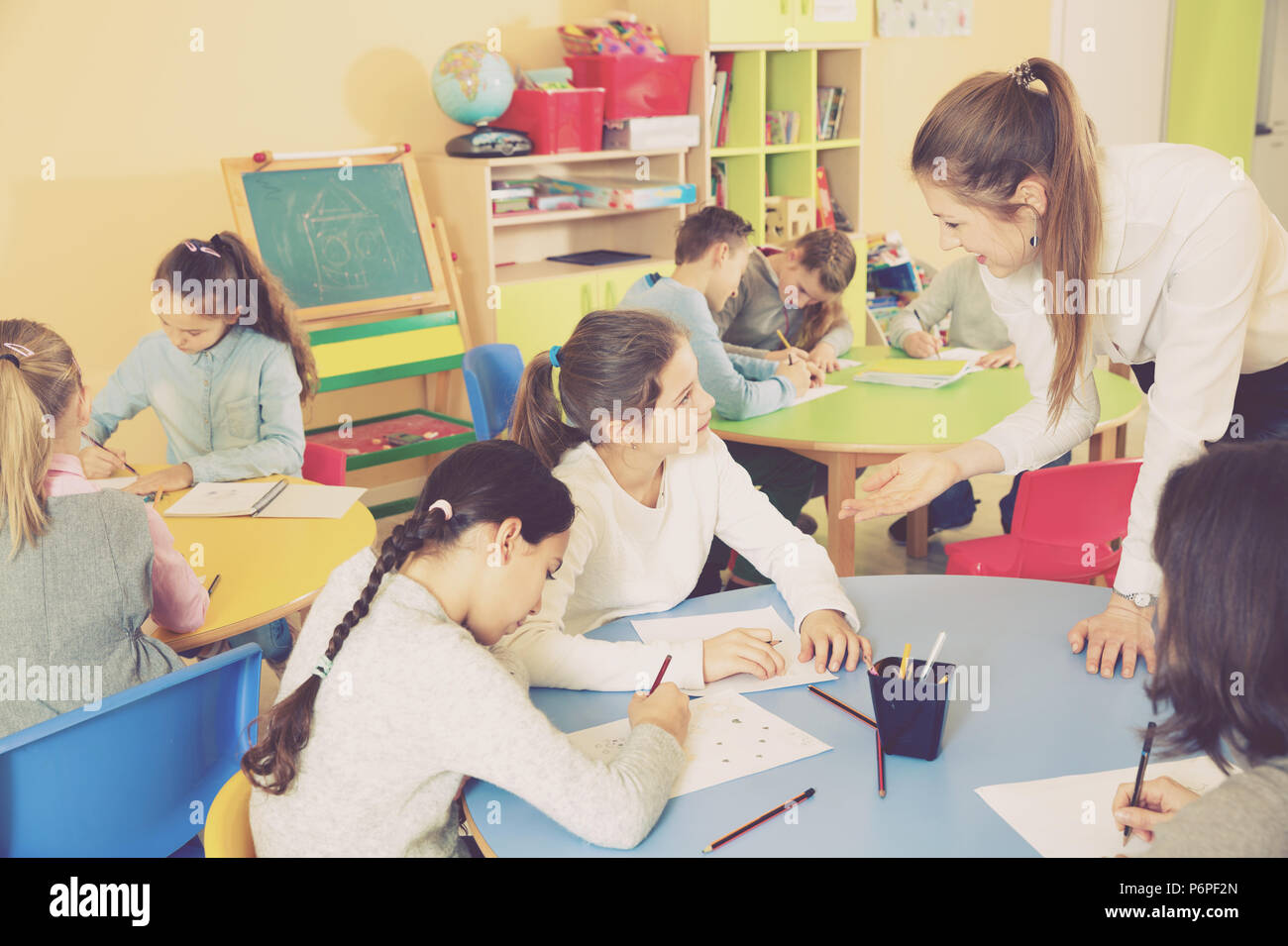 Group of diligent friendly smiling school kids with pens and notebooks ...