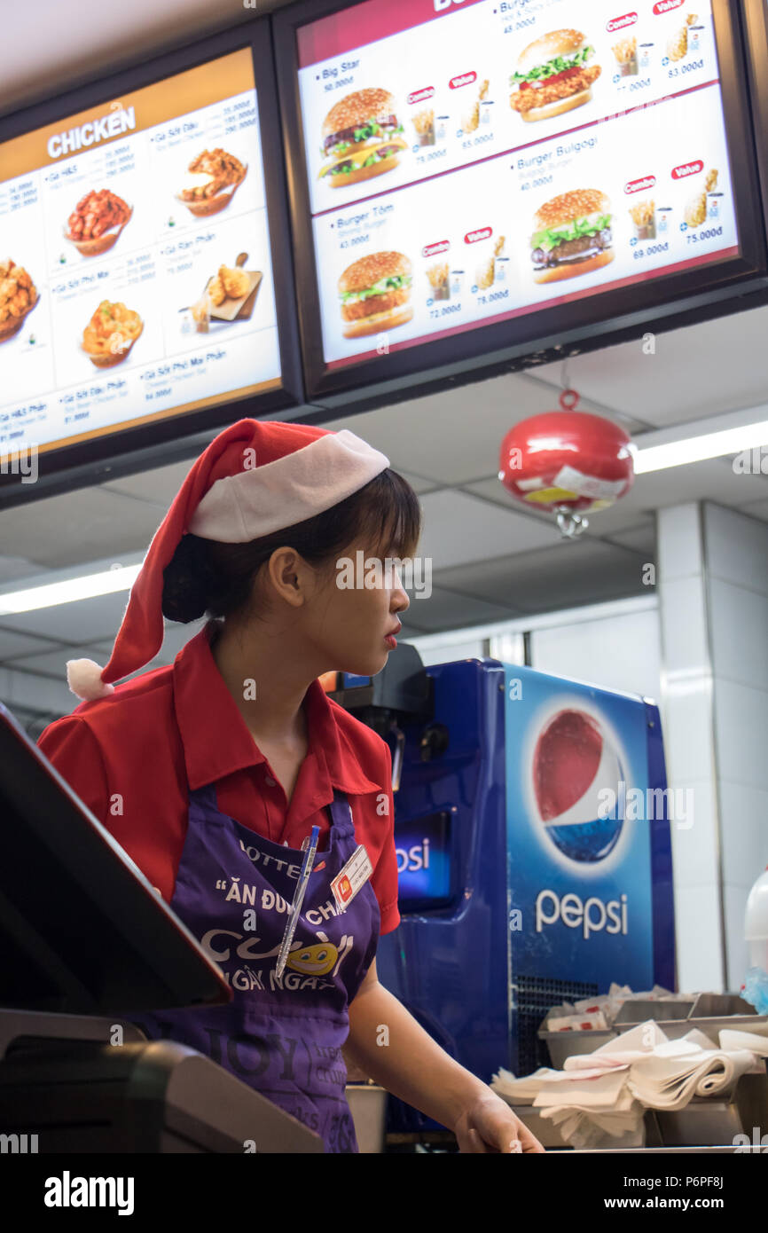 SAIGON, VIETNAM, DEC 14 2017, young woman in Santa Claus cap working at a fast food restaurant. Stock Photo