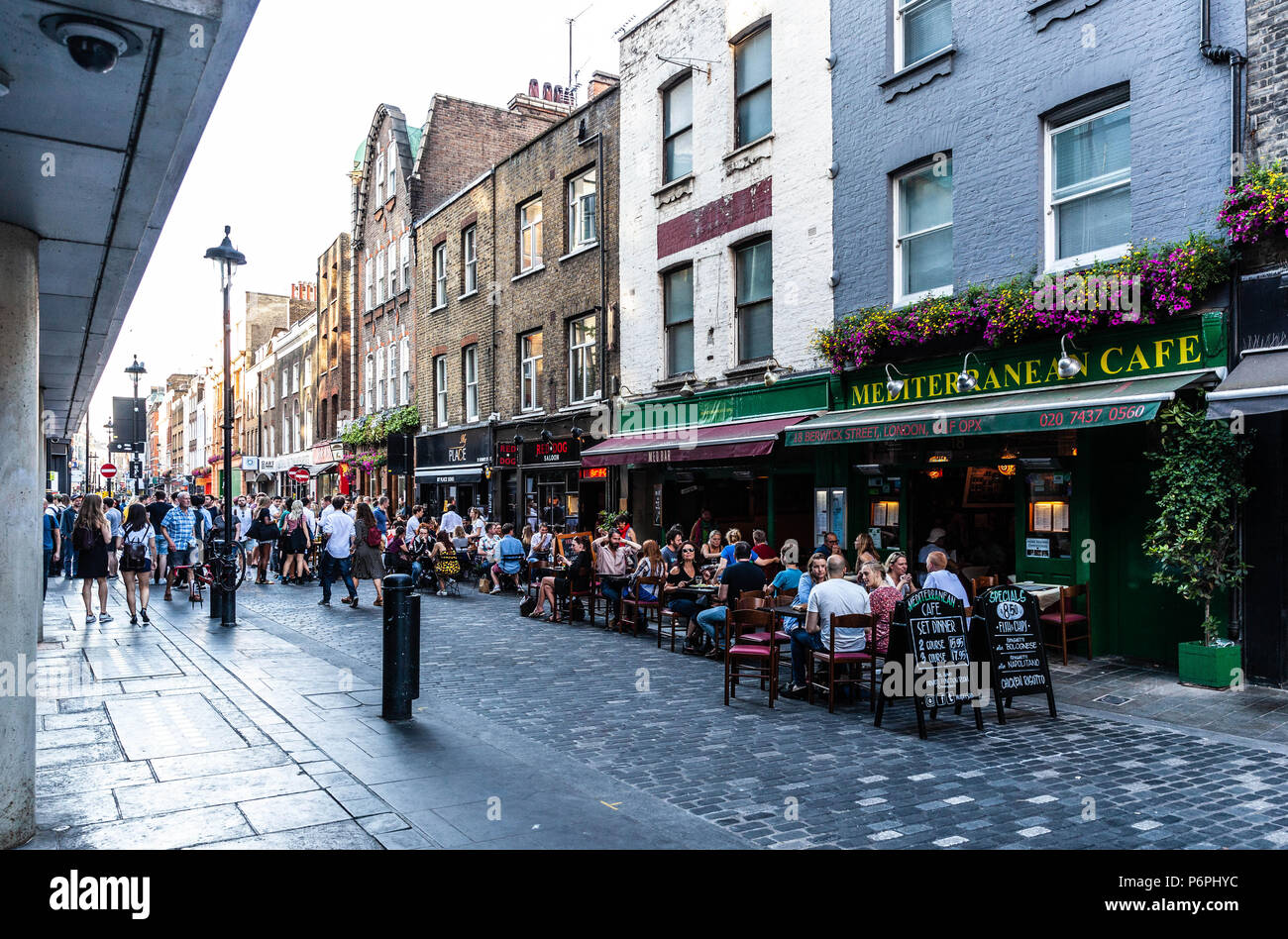 Customers dining al fresco at row of restaurants on Berwick Street, Soho, London, England, UK