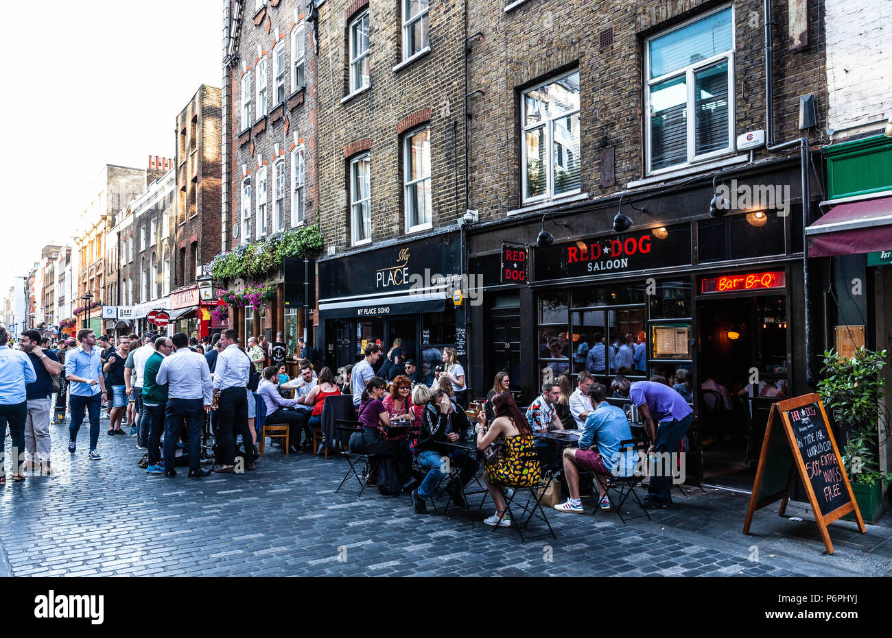 Customers dining al fresco at row of restaurants on Berwick Street, Soho, London, England, UK. Stock Photo