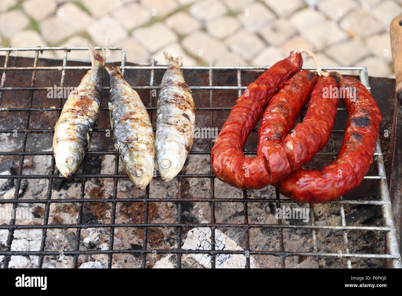 Portugal outdoor grill - typical view in Lisbon. Charcoal grilled sardines and chourico sausages. Stock Photo