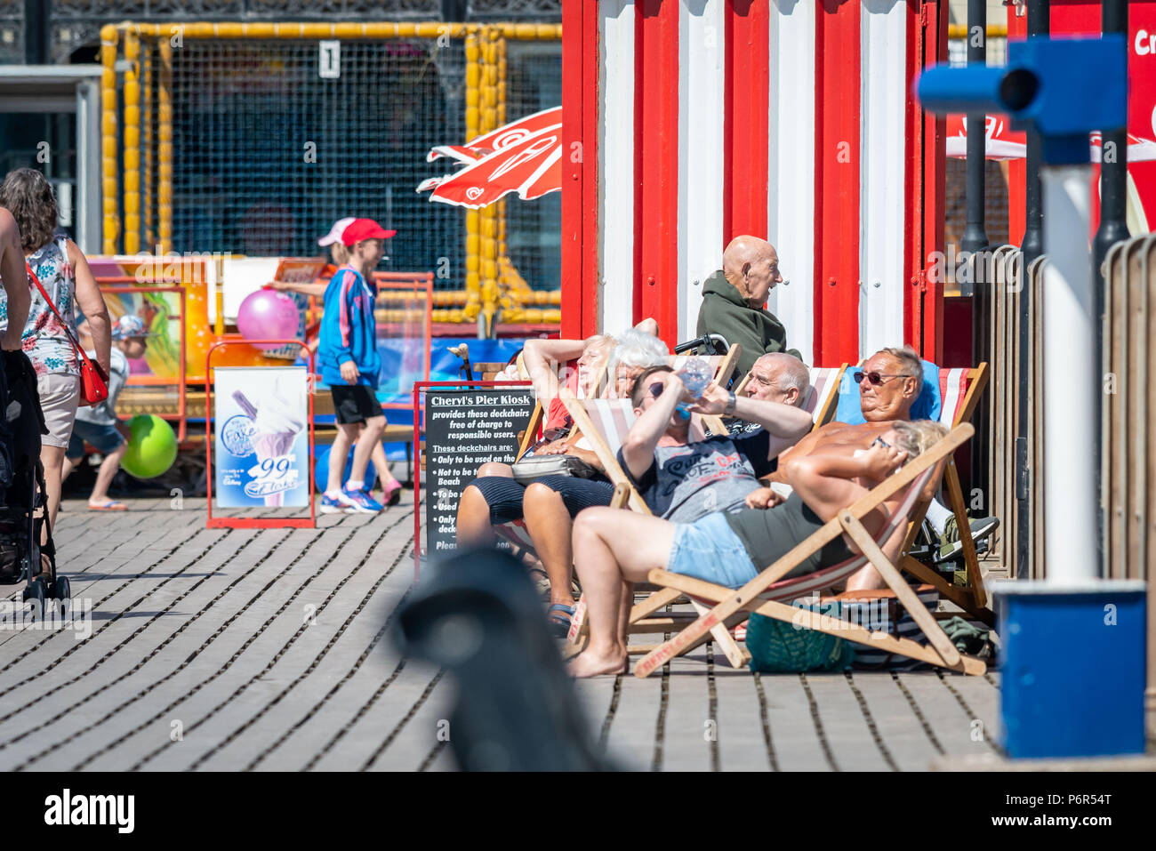 Skegness, UK. 2nd July 2018. On Skegness Pier a group of old age pensioners sit in their deck chairs and enjoy the hot weather, bright sunshine, and raising temperatures as they relax and take it easy during the current heatwave that is hiting the whole of the UK. Credit: Steven Booth/Alamy Live News. Stock Photo