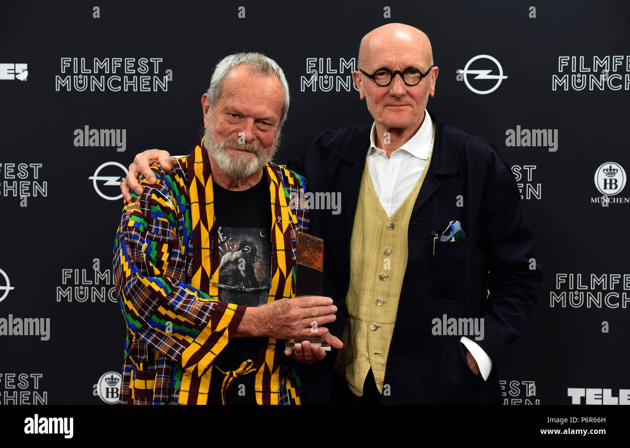 Munich, Germany. 02nd July, 2018. Award winner Terry Gilliam (L), film director and co-founder of the Monty Python franchise, and Ray Cooper, English percussionist, holding together the CineMerit Prize after the award ceremony. Credit: Felix Hörhager/dpa/Alamy Live News Stock Photo