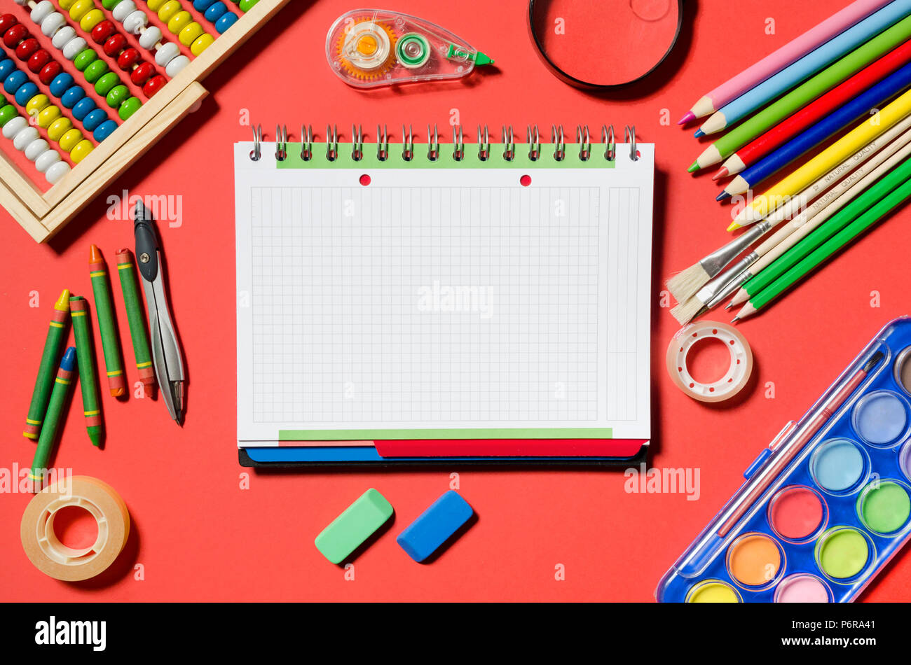 Notepad and school supplies, office stationery, red background. Blank notepad for your text. Stock Photo