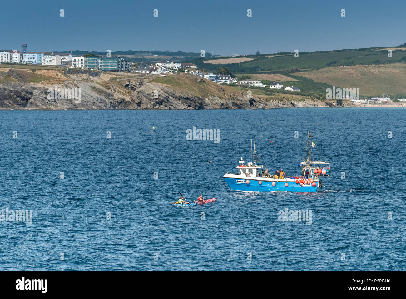 A fishing boat PW51 and two kayaks off the coast of Newquay in Cornwall