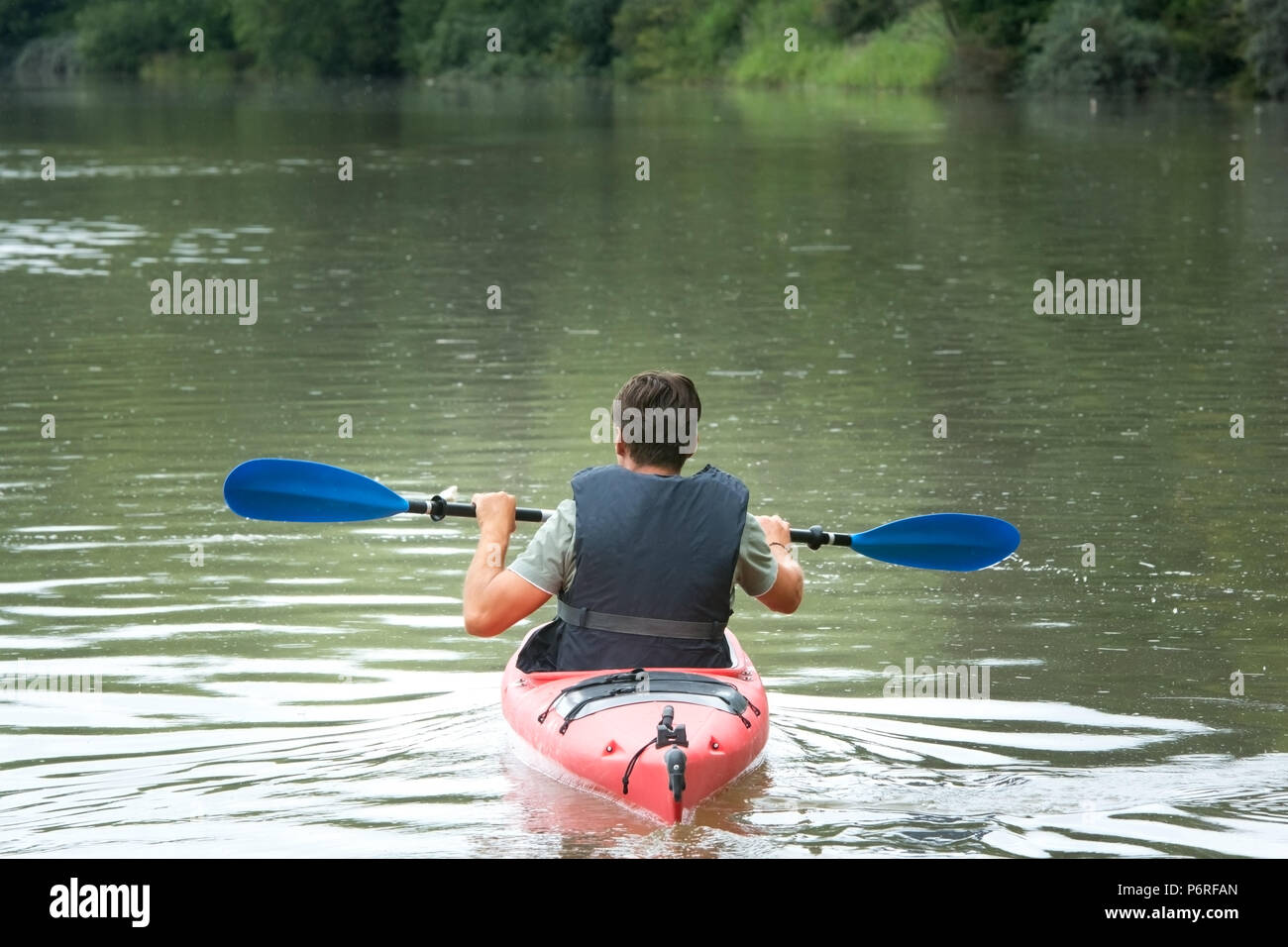 Adult male in red canoe on mountain lake Stock Photo