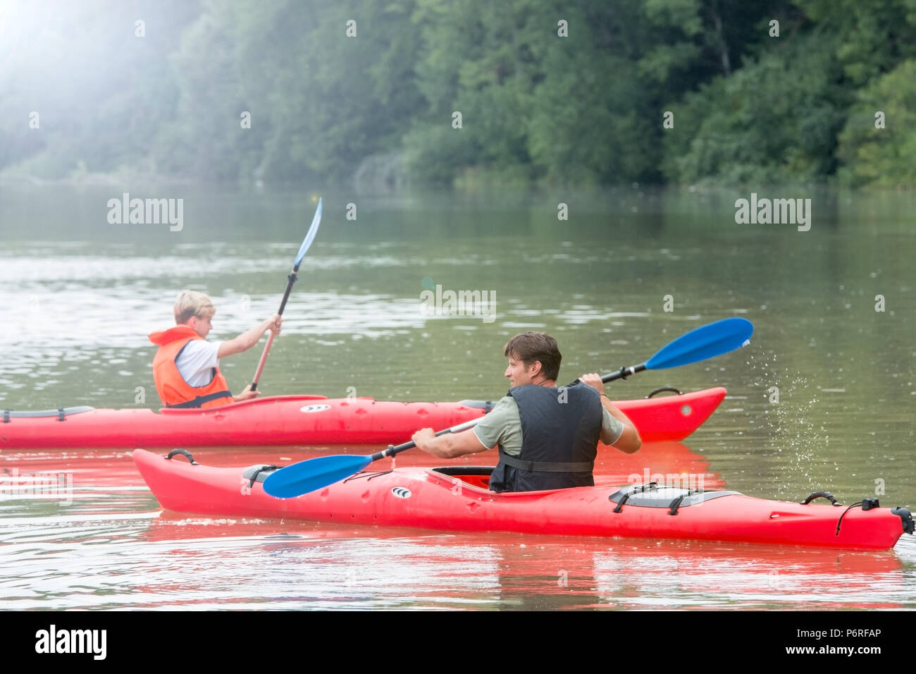 Father and son, each paddle a canoe on mountain lake Stock Photo
