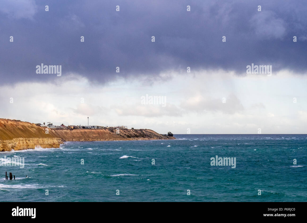 Storm clouds crossing the coastline from the St Vincent Gulf over the Port Willunga limestone cliffs and the Port Willunga Jetty Pylons, SA, Australia Stock Photo