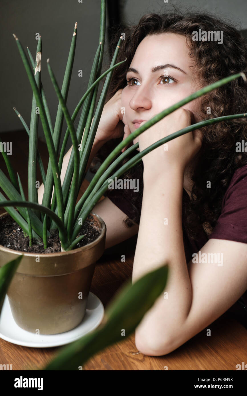 beautiful young brunette girl with a green plant in pot Stock Photo - Alamy