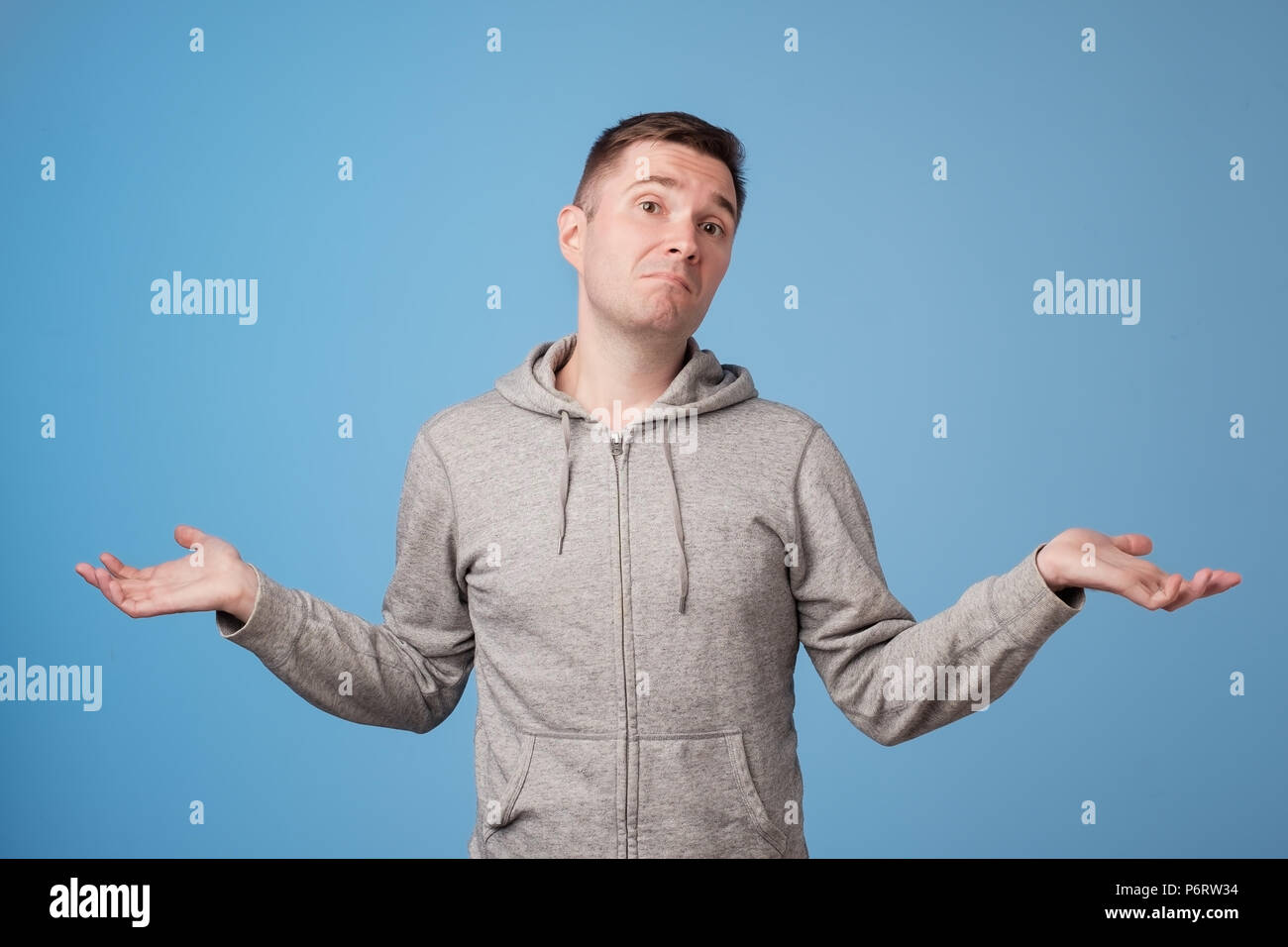 Studio portrait of confused handsome guy showing I have no idea gesture. Stock Photo