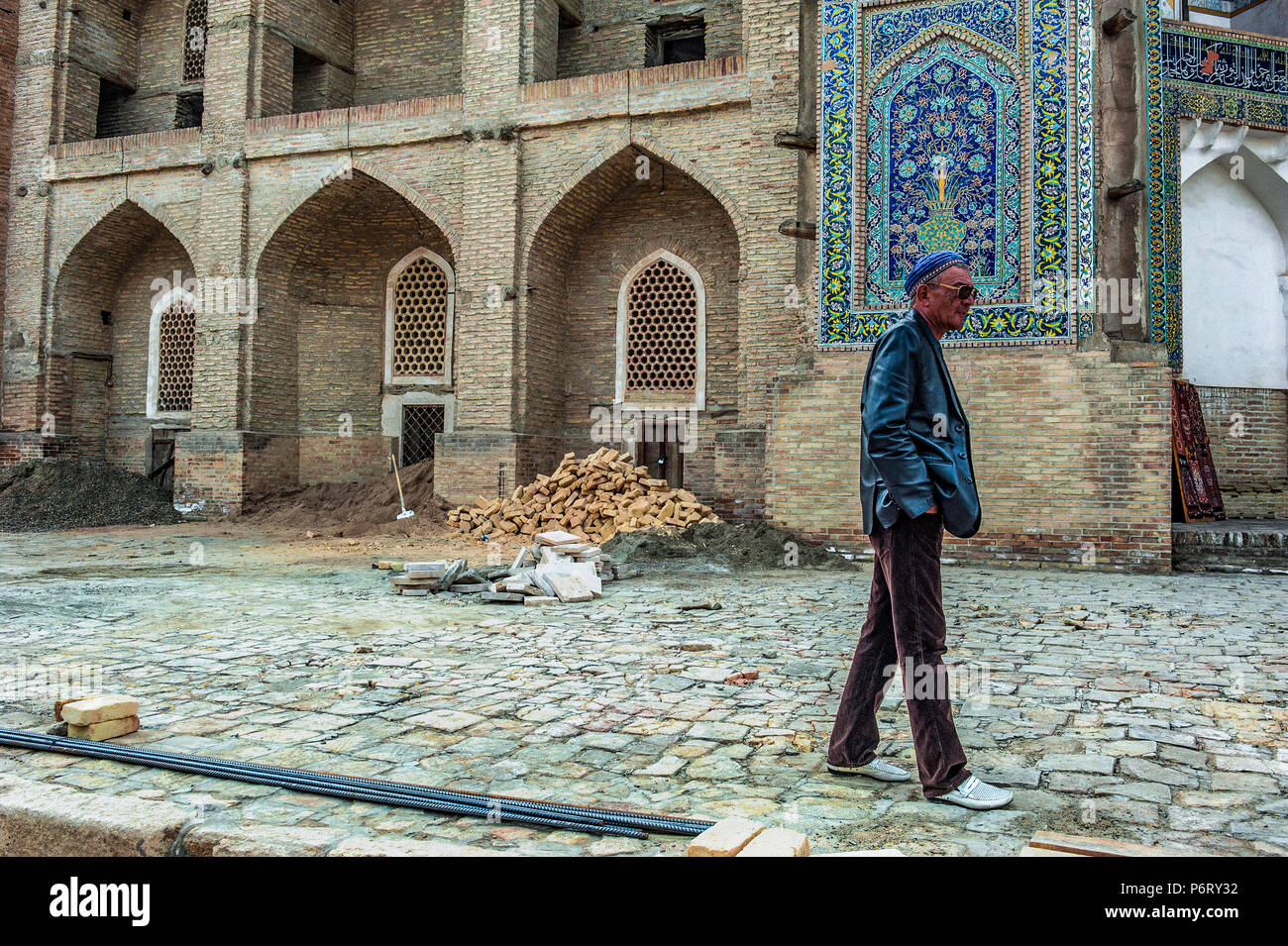 A man walking among the works in progress in front of a building, in Bukhara, Uzbekistan Stock Photo