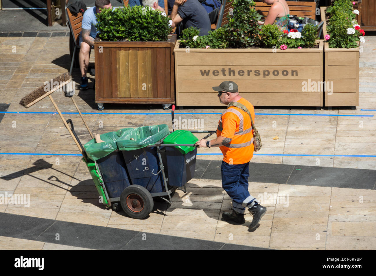 A street sweeper and his cart in front of a Weatherspoons pub in Hammersmith, London, W6, UK Stock Photo