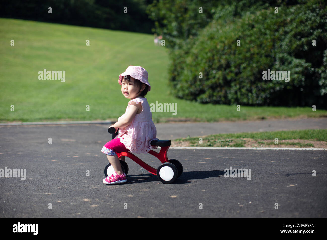 Baby girl play bicycle at outdoor playground Stock Photo - Alamy