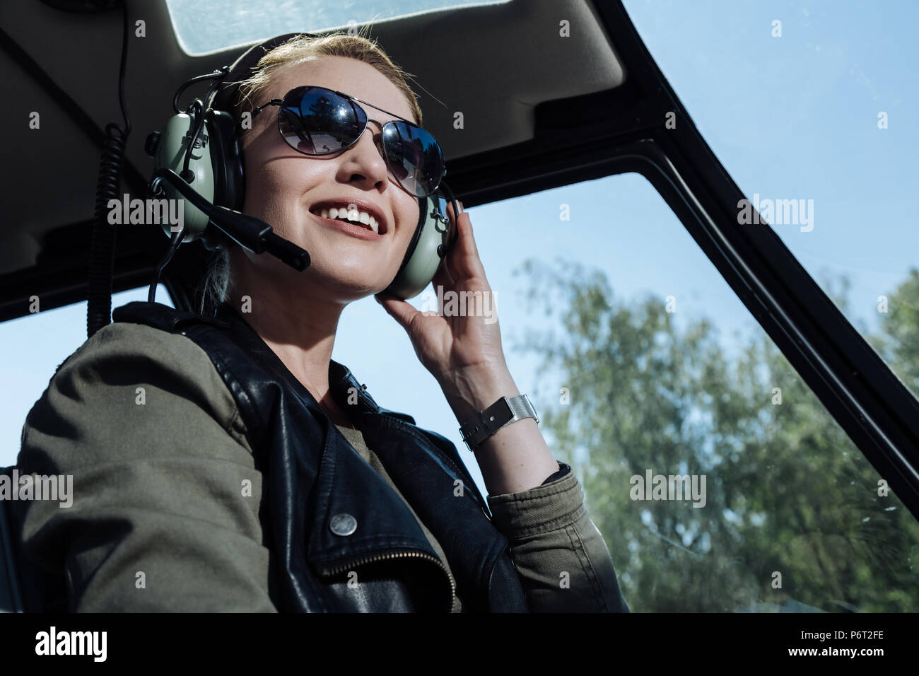 Cheerful helicopter pilot smiling while listening to air traffic controller Stock Photo