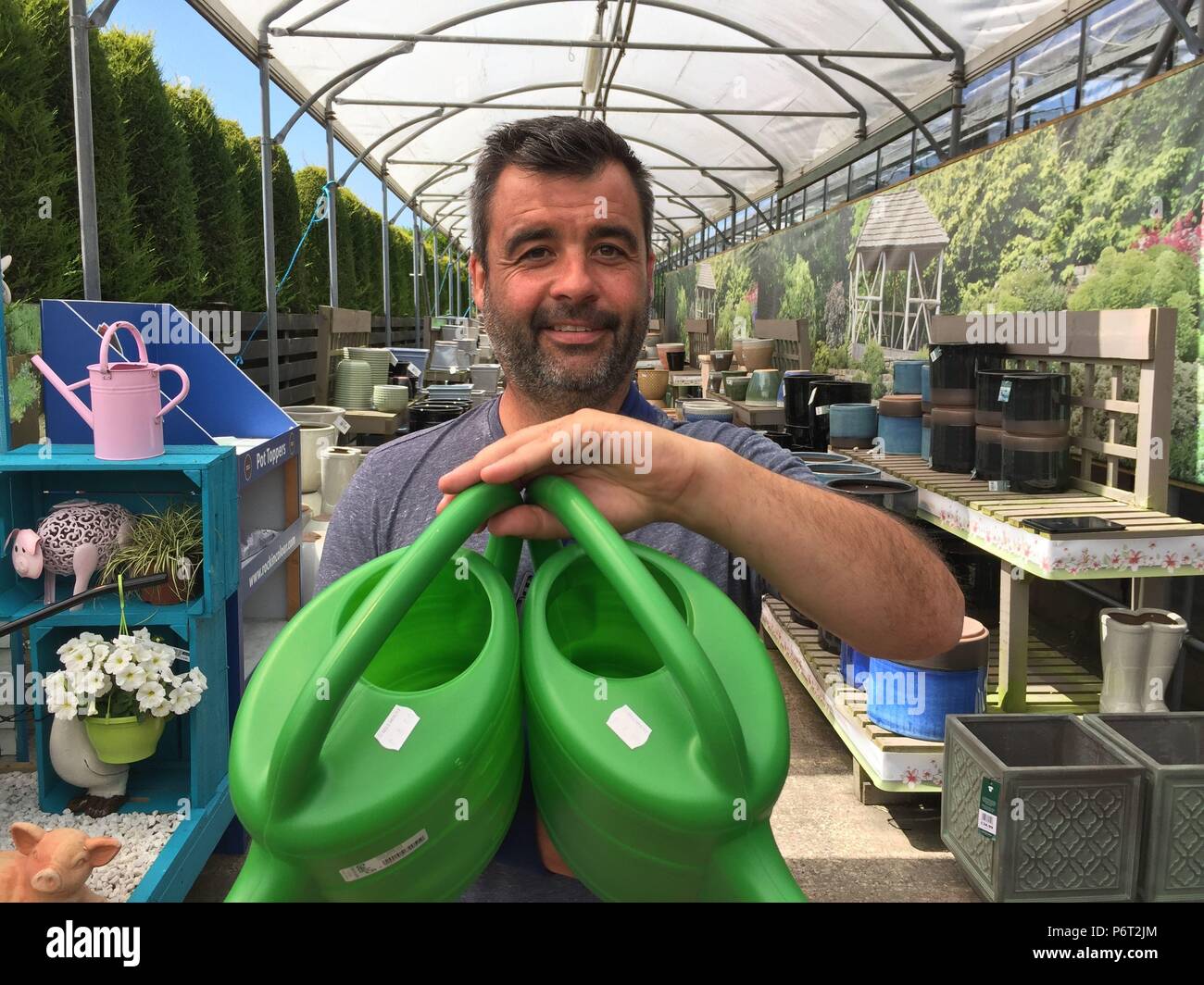Sales representative for Stewart Plastics Neil Griffiths holding watering cans, as a hosepipe ban in Northern Ireland has prompted an unprecedented rush on another gardener&Otilde;s friend, the watering can. Cans of all shapes and sizes have been flying off the shelves across the region as gardeners turn to more labour intensive means to keep their plants and lawns hydrated. Stock Photo