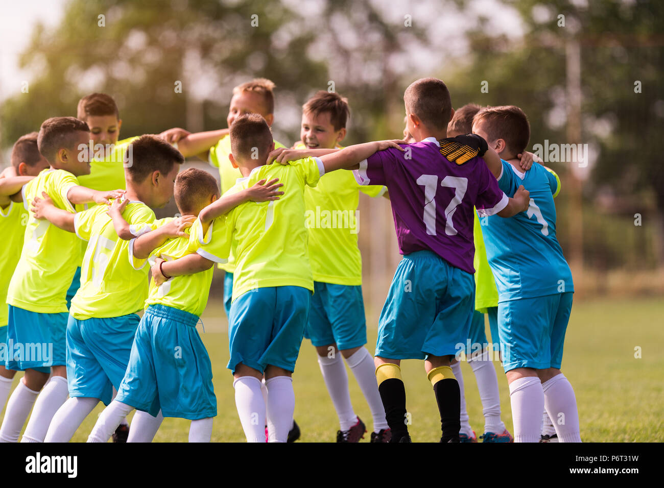 Kids soccer football - young children players celebrating in hug after victory Stock Photo