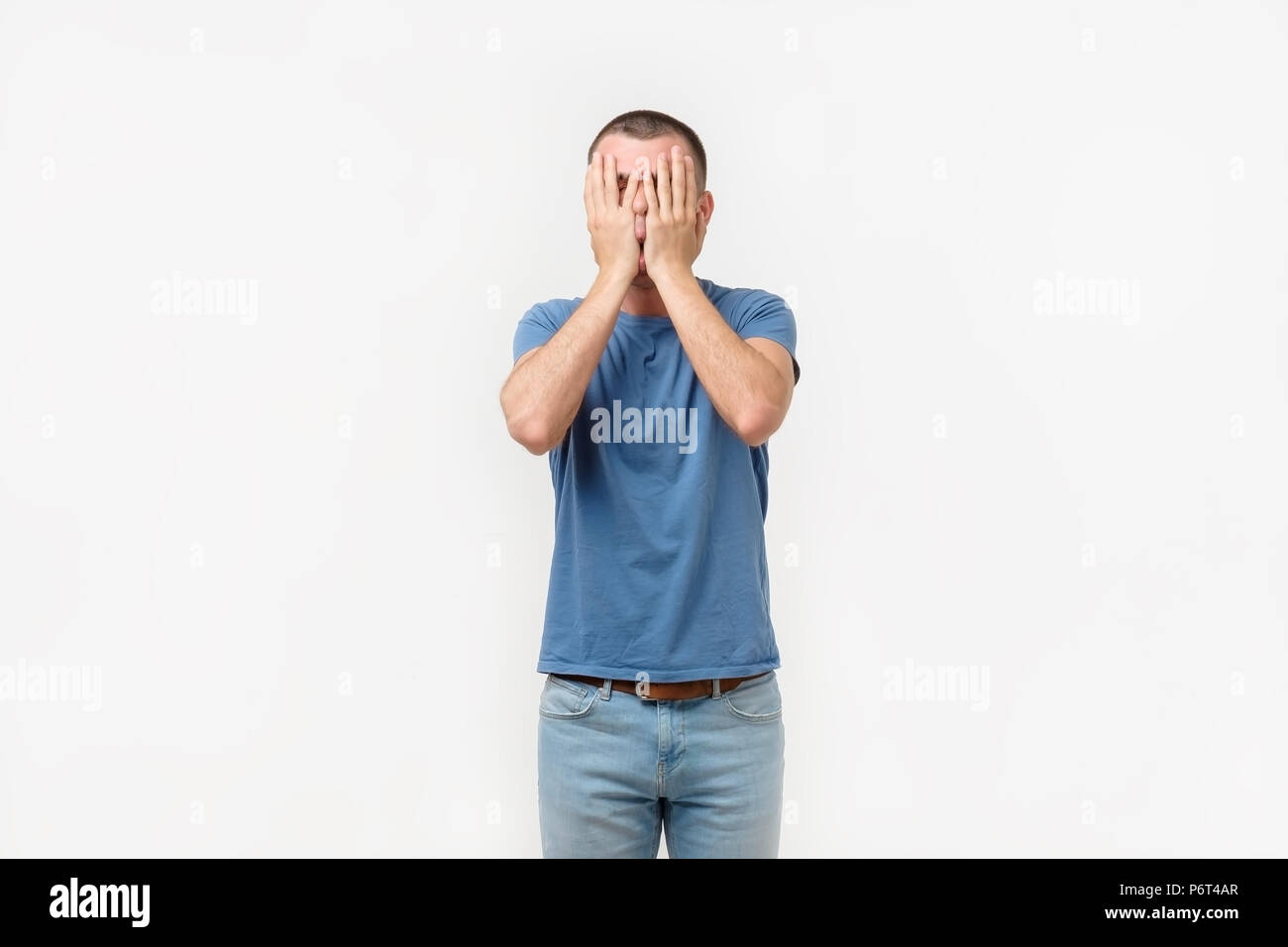 Studio portrait of hidpanic young man covering his face in dissapoint using facepalm sign Stock Photo