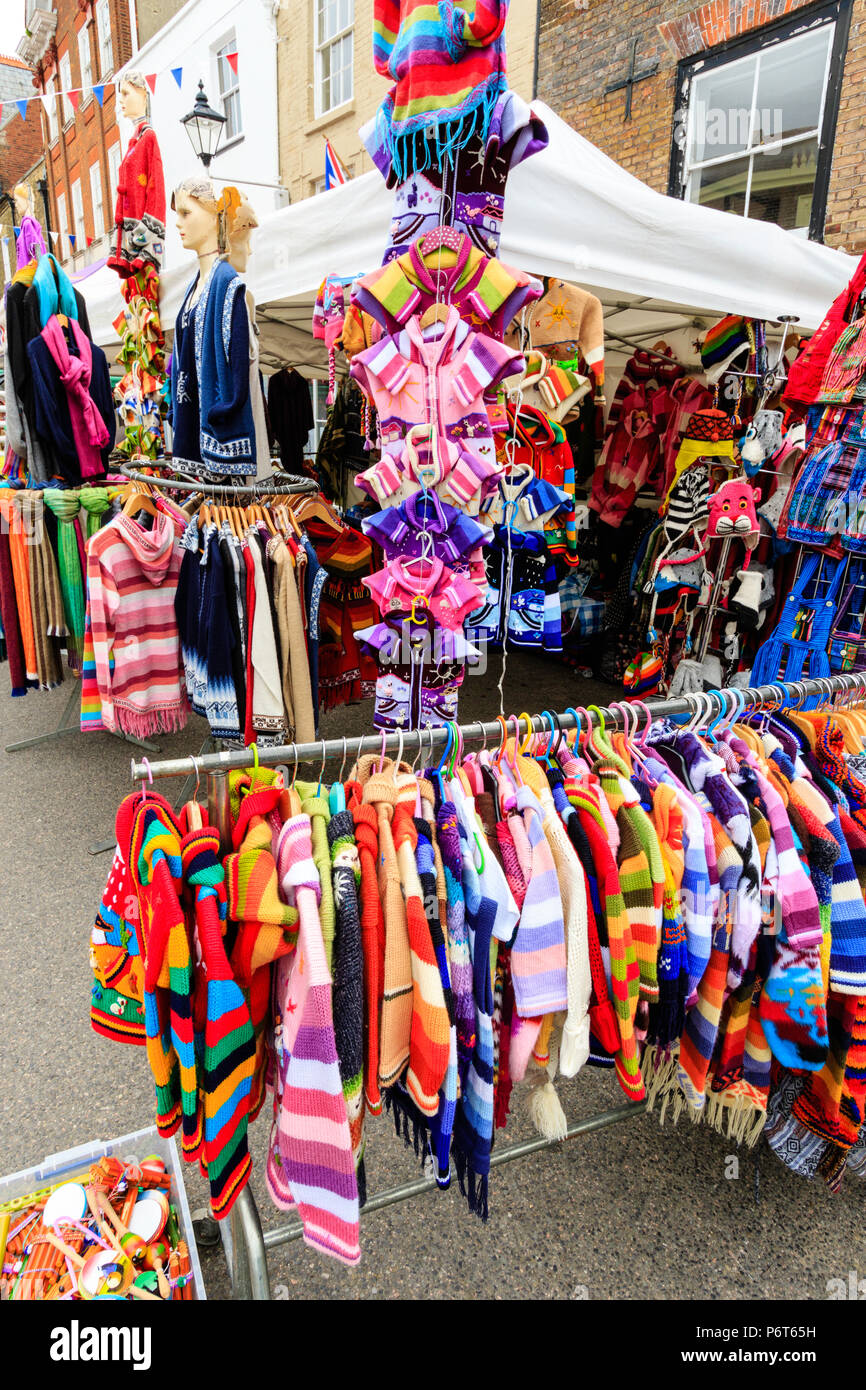 Racks and hangers full of multi-coloured clothing at market stall. Wide ...