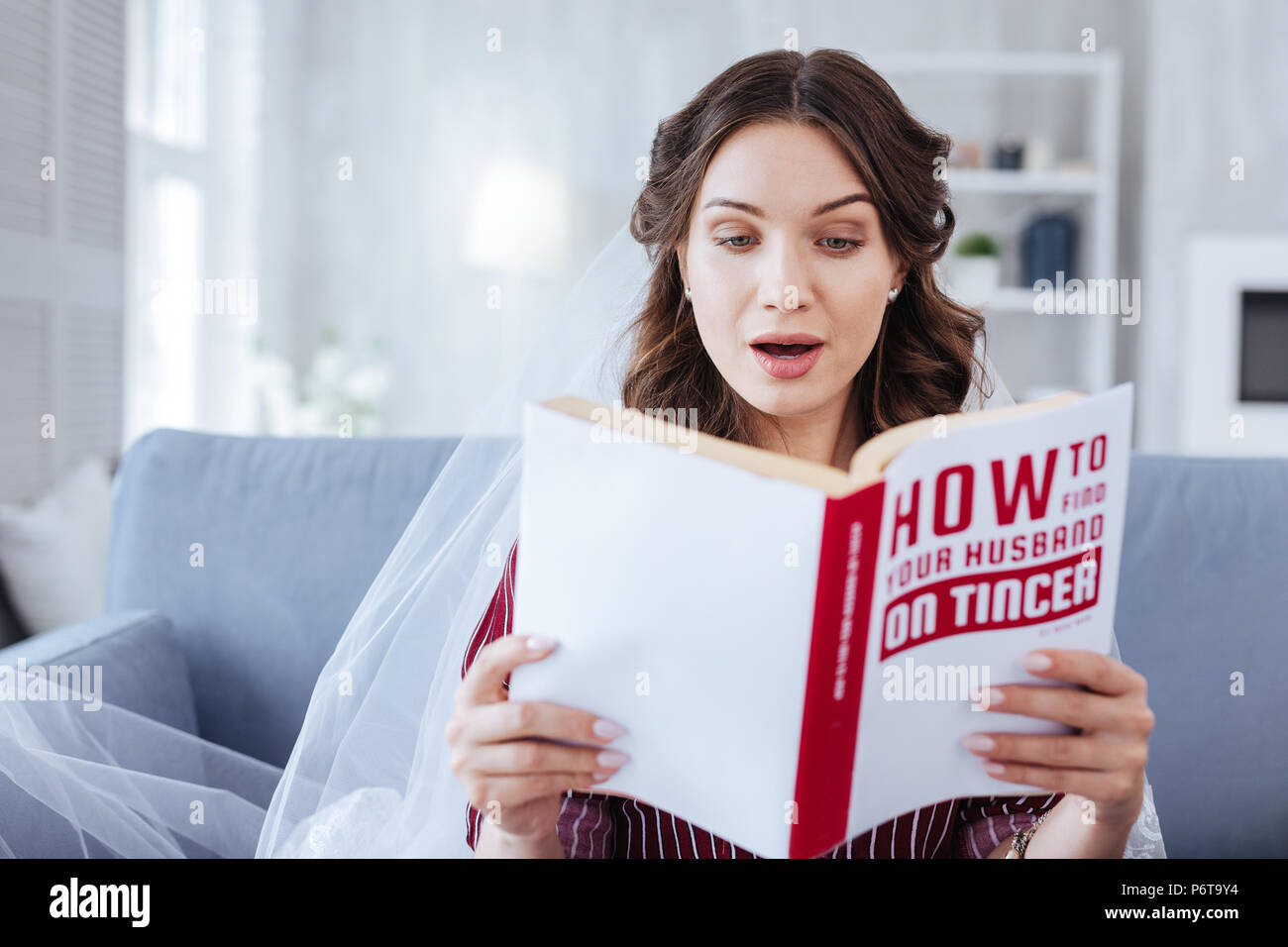 Dark-eyed woman feeling curious while reading book Stock Photo