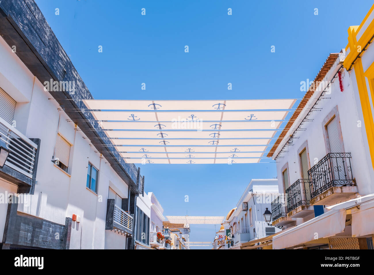 strips of sun shade over a street in portugal attached to roof tops via wires Stock Photo