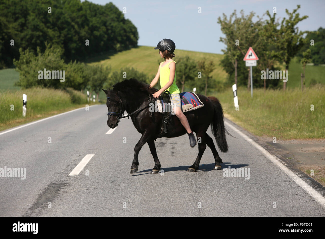Oberoderwitz, young girl crossing a country lane on her Shetland pony Stock Photo