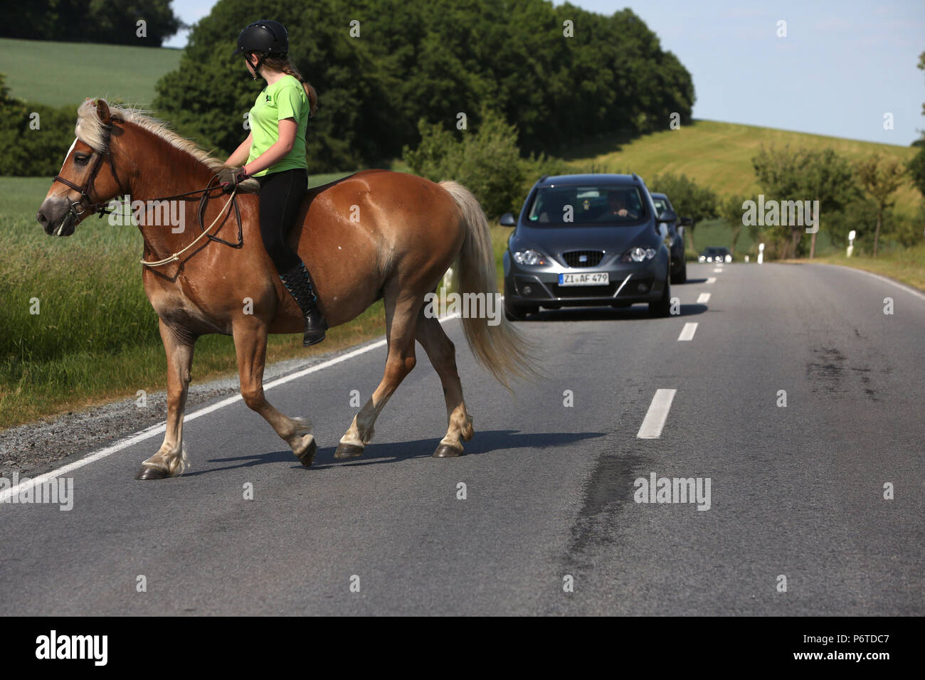 Oberoderwitz, young woman crosses a country road on a ride Stock Photo